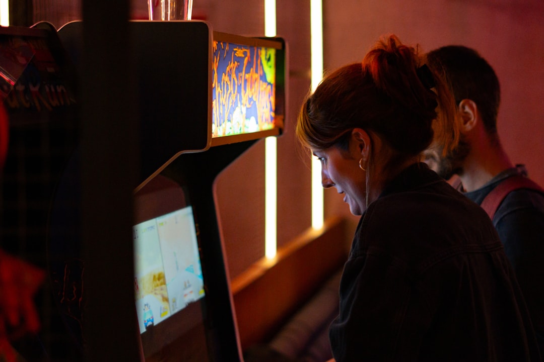 A neon-lit arcade cabinet glowing purple and pink in a dim room